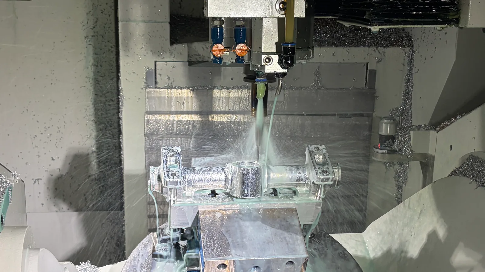 CNC machining setup showing a cutting tool, clamped workpiece and coolant