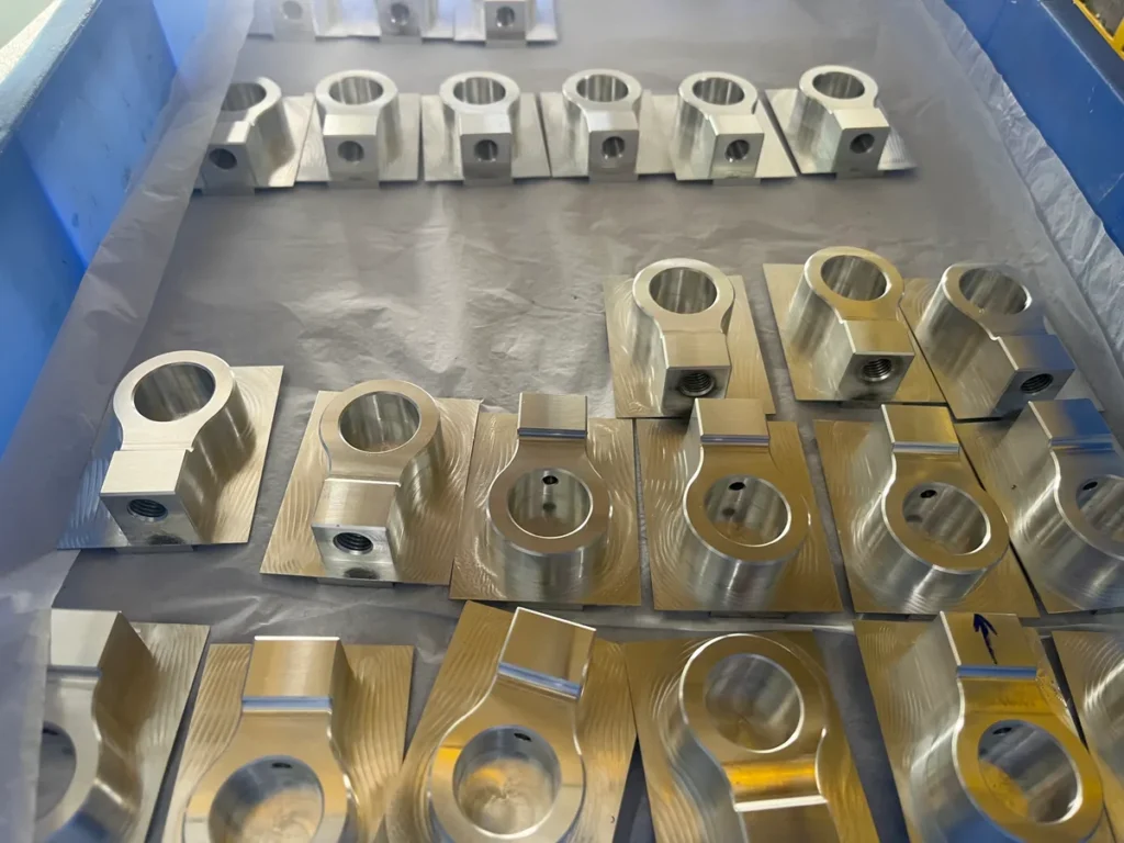 Batch of machined metal parts with circular bores and side holes arranged in a lined tray