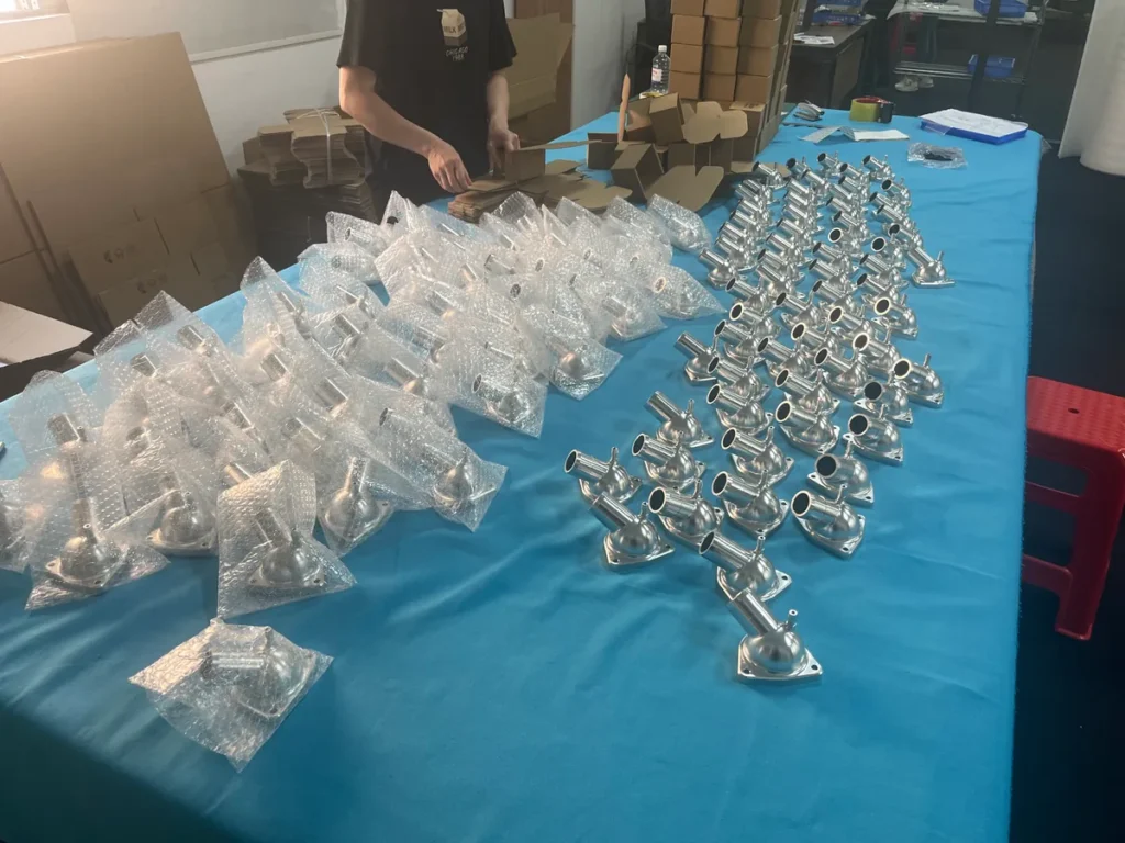 CNC machined metal parts arranged on a packing table with individual bubble wrapping