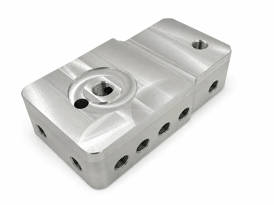 CNC-milled industrial equipment connector block with threaded ports on multiple faces