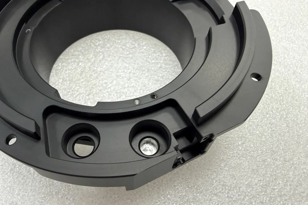 Black-anodized CNC component showing controlled bores and precision features