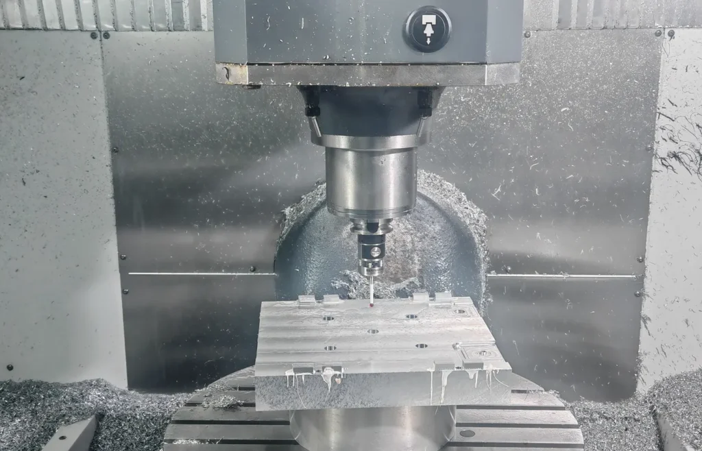 Spindle-mounted touch probe positioned over an aluminum workpiece inside a CNC machining center