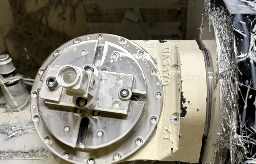 Indexed 3+2 CNC machining setup with a rotary table holding a multi-sided aluminum part