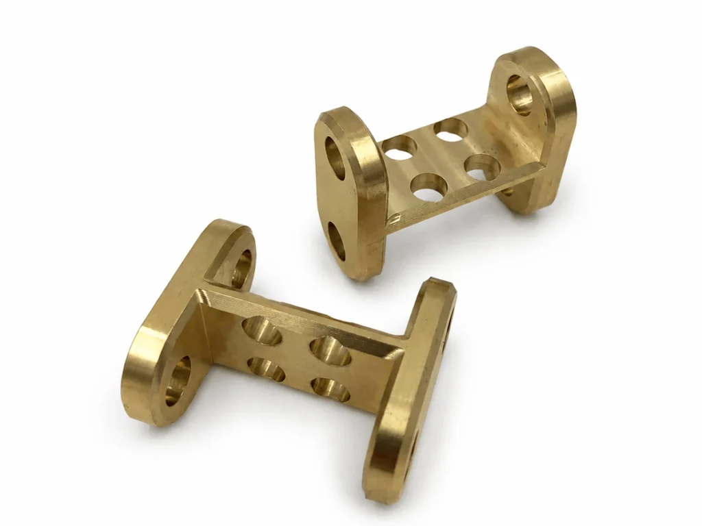 Two machined copper components with multiple holes and visible surface marks