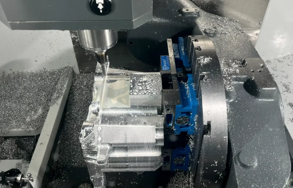 Simultaneous 5-axis CNC machining of an aluminum part with the spindle, fixture and rotary trunnion visible