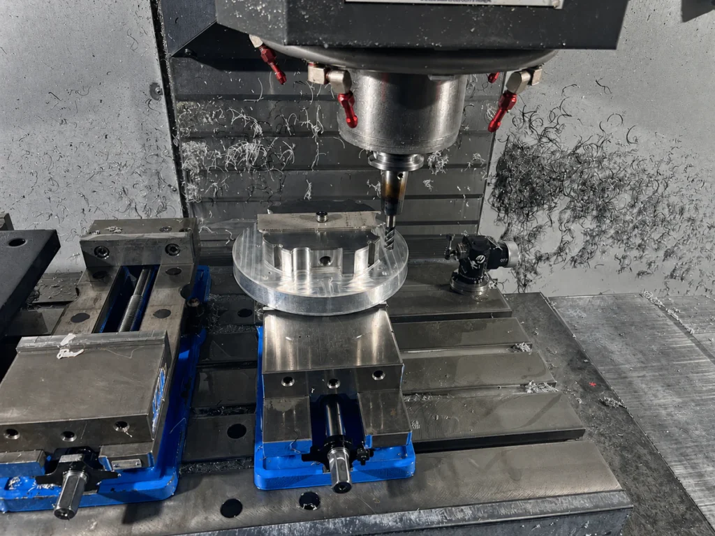 Three-axis CNC milling machine with a circular aluminum workpiece held in a vise