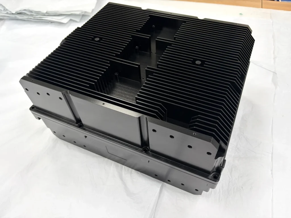 Black-finished aluminum enclosure component with external fins and machined mounting holes
