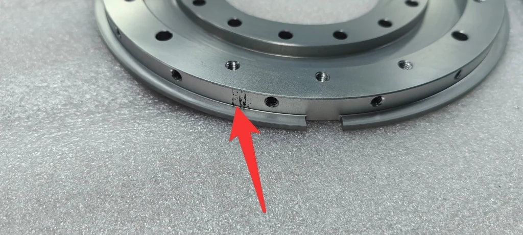 Localized dark marks indicated by a red arrow on a clear anodized 7075-T6 component