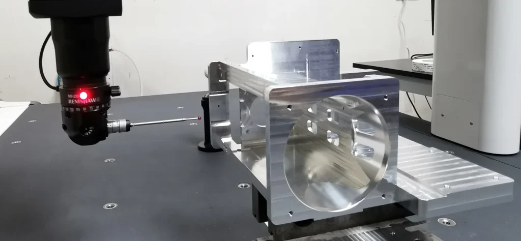 CMM probe beside the aluminum bracket in a dimensional inspection setup