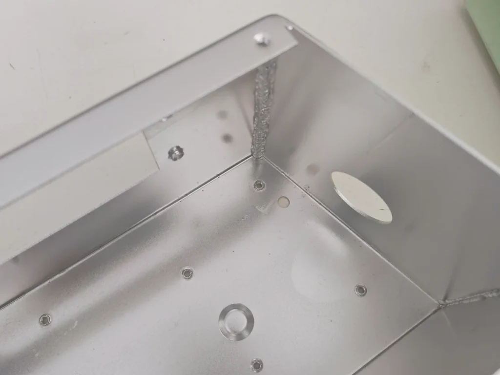 Interior corner weld, bent flange and holes in a sheet metal enclosure