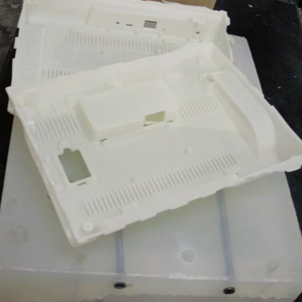 White vacuum cast housing with rows of narrow vent slots placed on its silicone mold