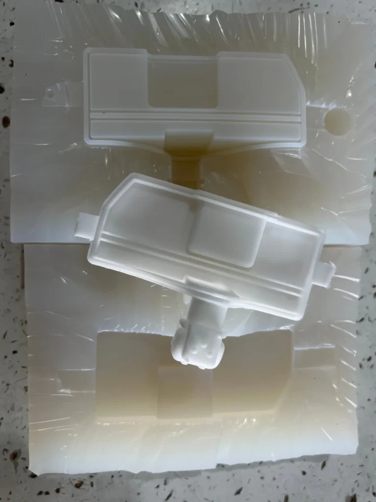 White vacuum cast component placed on an opened translucent silicone mold