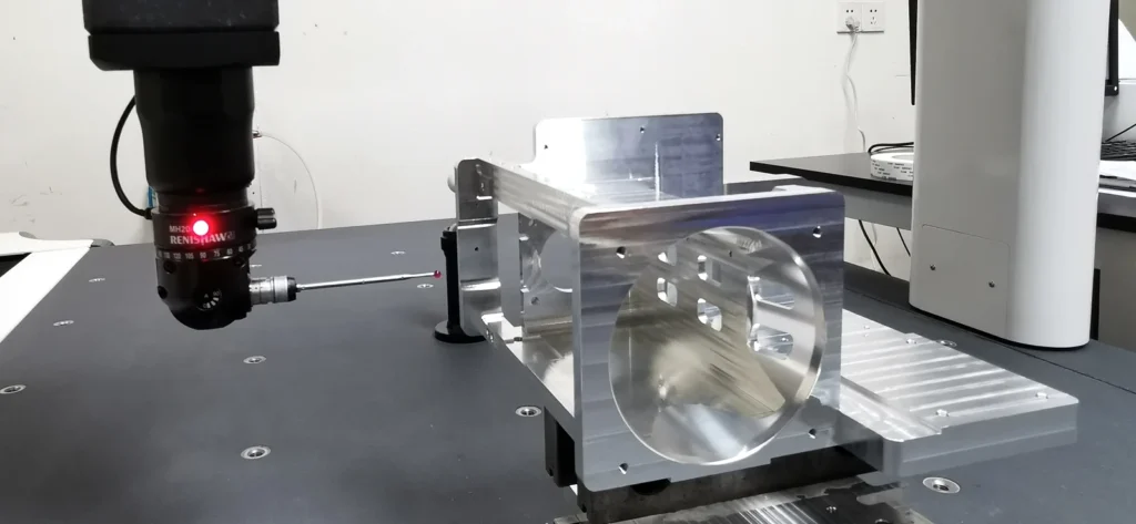 CMM probe beside a machined bracket supported on the measuring table