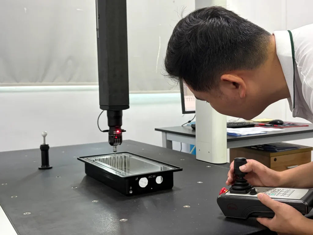 Operator using a coordinate measuring machine to inspect an aluminum enclosure