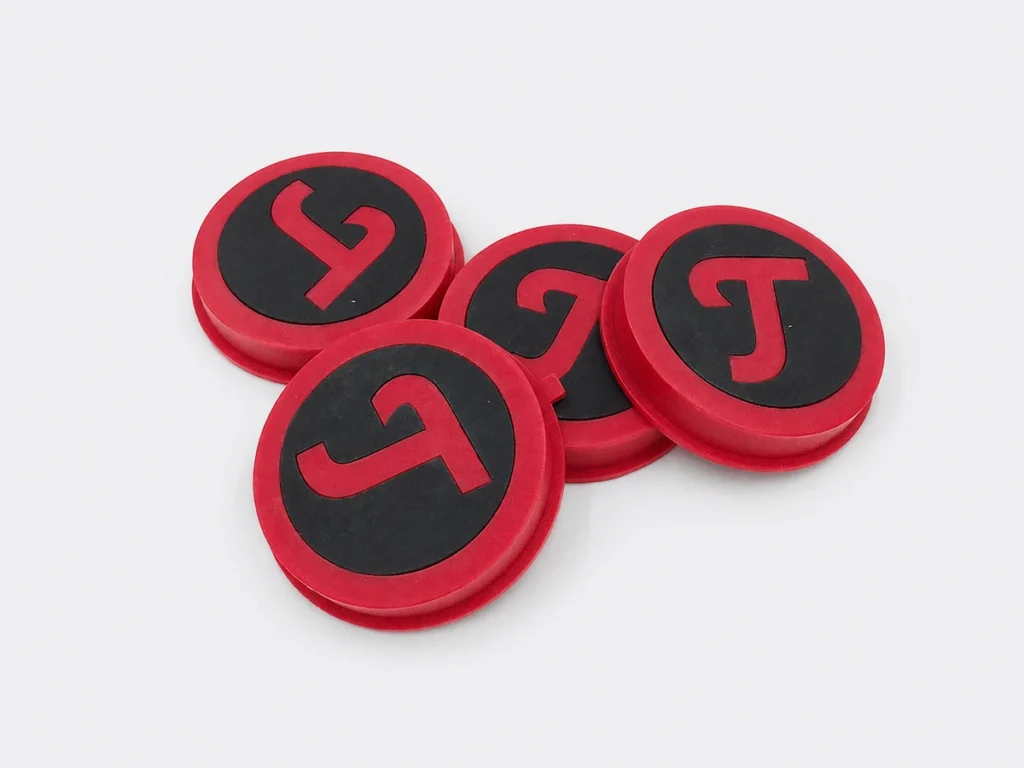 Four red and black circular components with contrasting molded surface regions.