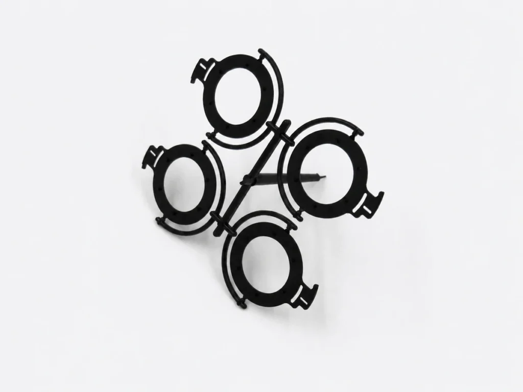 Four matching black ring-shaped plastic parts connected to a runner.