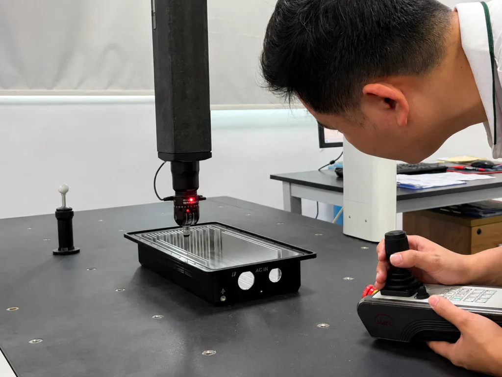 Operator inspecting a CNC-machined aluminum heat sink on a coordinate measuring machine