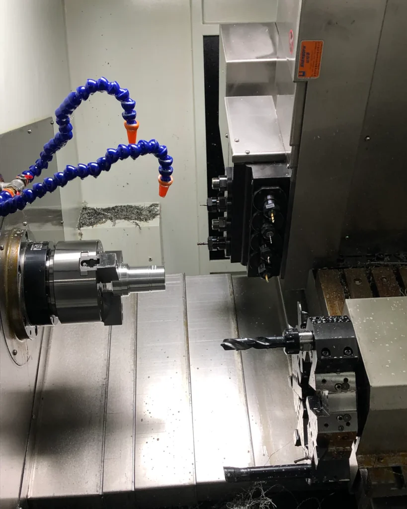 CNC turning center interior with a chuck-held cylindrical workpiece and tool turret