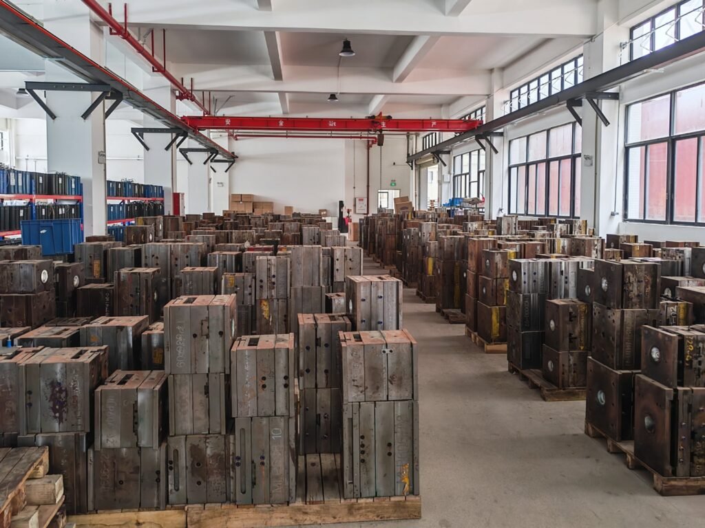 Injection molds arranged on wooden pallets on both sides of an aisle in a workshop storage area.