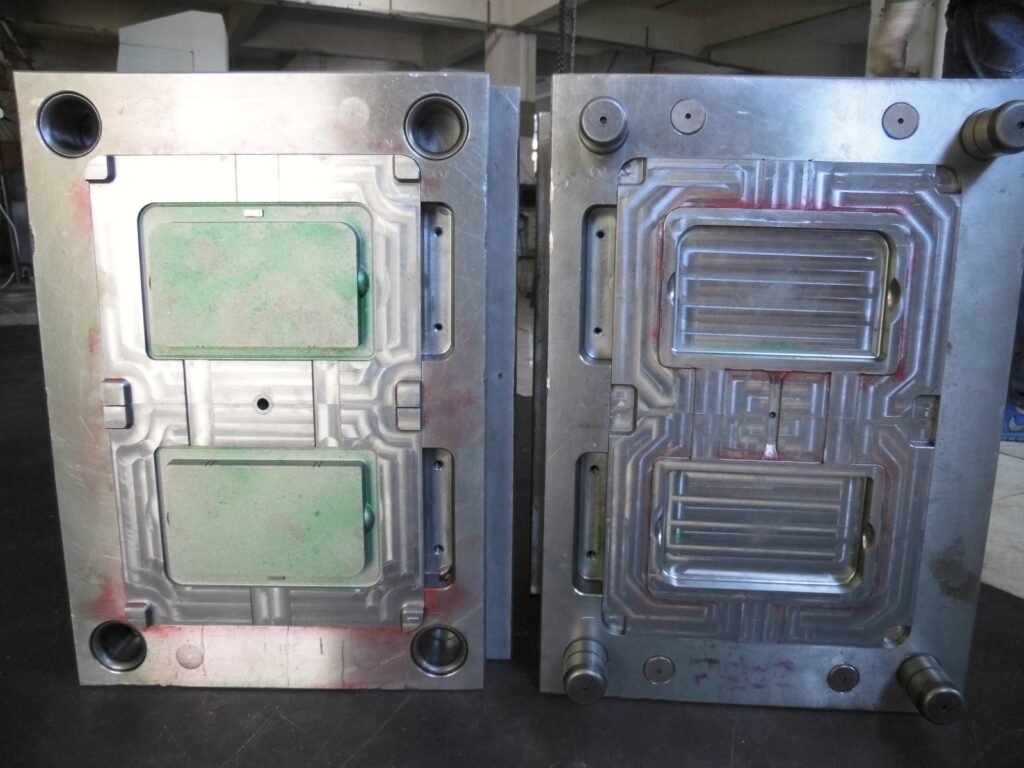 Two halves of an injection mold placed side by side, showing forming surfaces and guide components.
