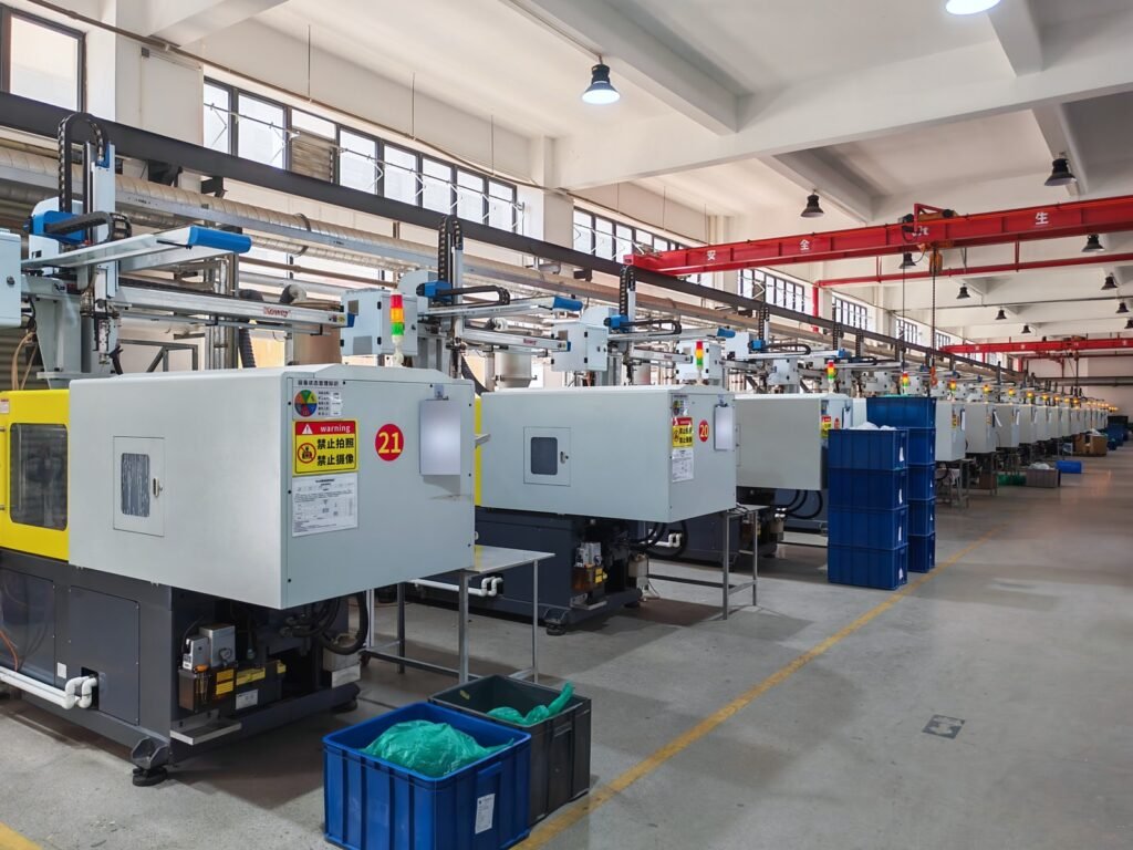 Rows of white injection molding machines with overhead robotic arms inside a production workshop.