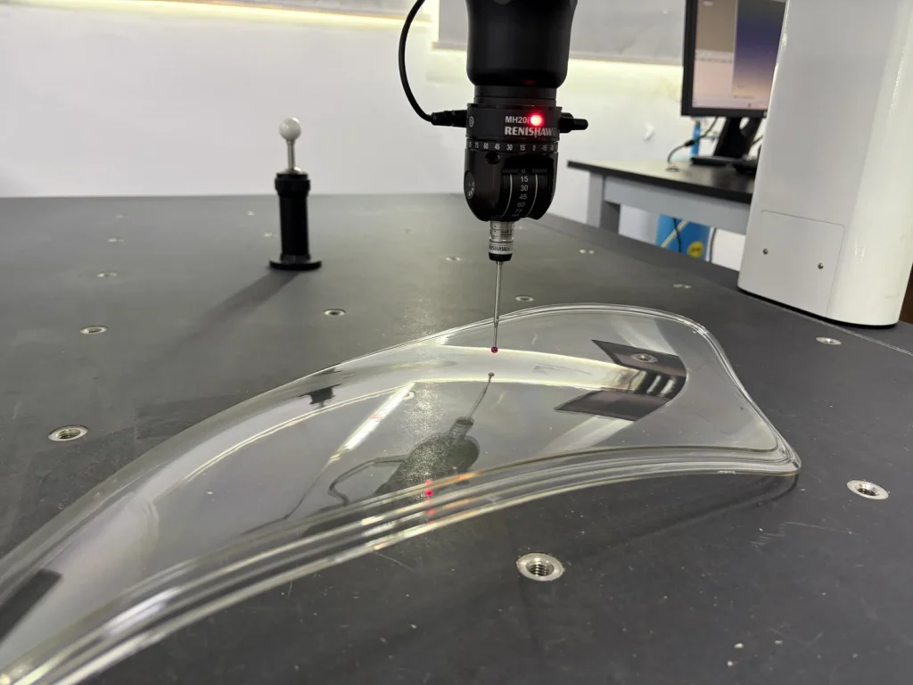 CMM probe positioned over a clear PC automotive lamp cover for dimensional inspection
