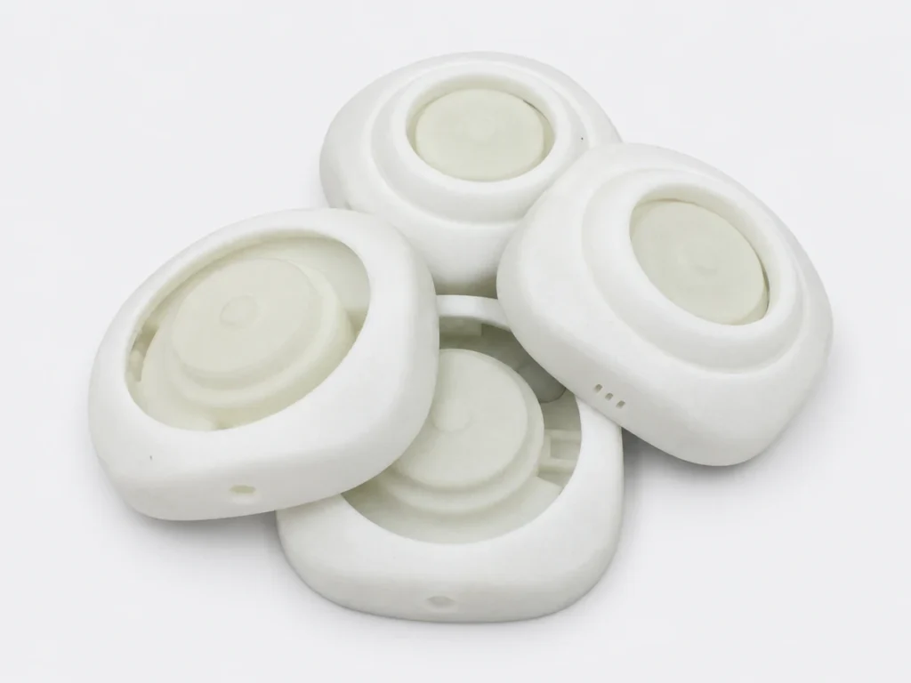 Four white 3D printed components with rounded housings, recessed centers and side openings.