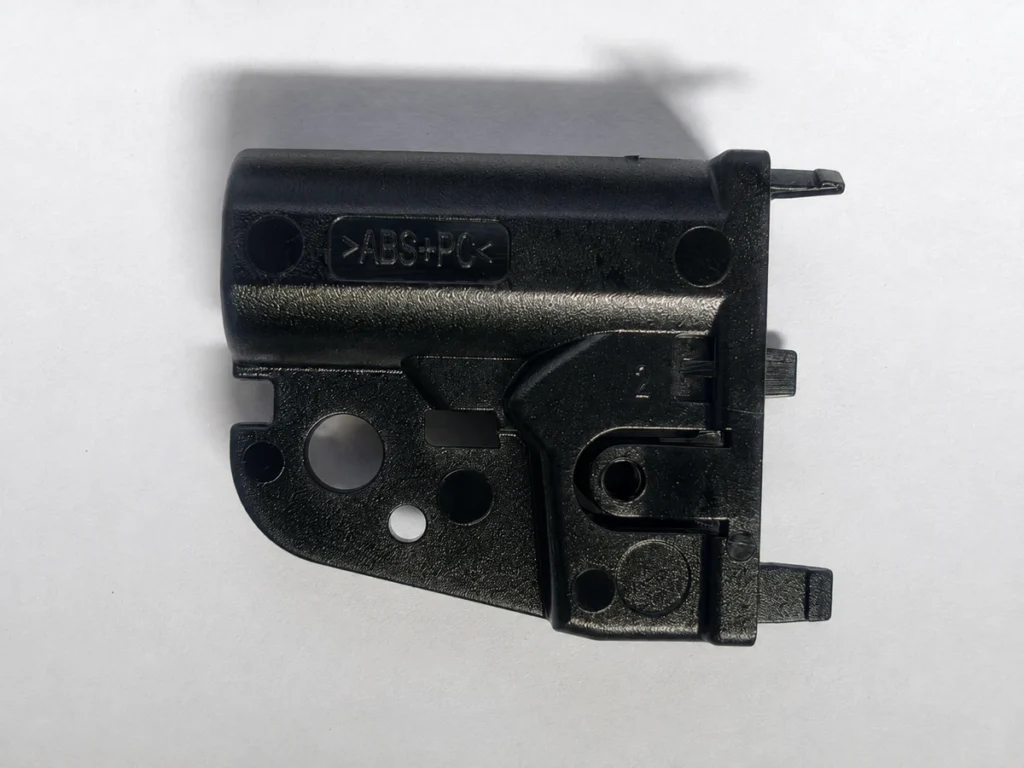 Black ABS+PC injection-molded part with ribs and circular openings, made by SAMSHION using rapid tooling.