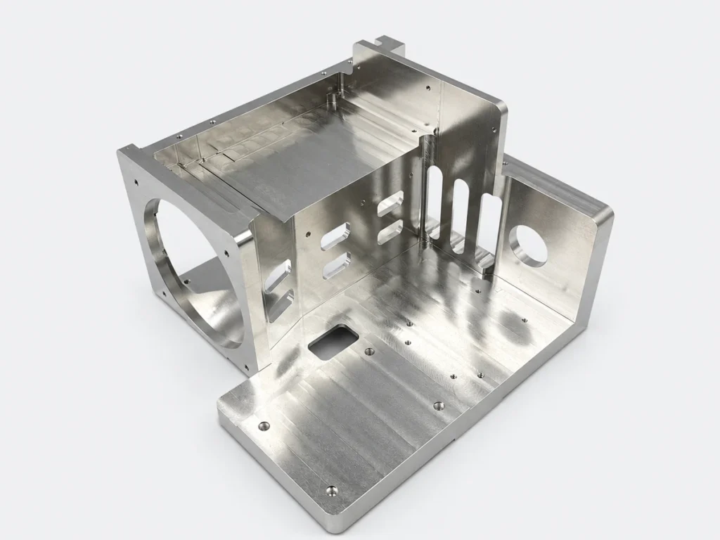Silver CNC machined prototype with an open cavity, circular cutouts, slots and mounting holes.