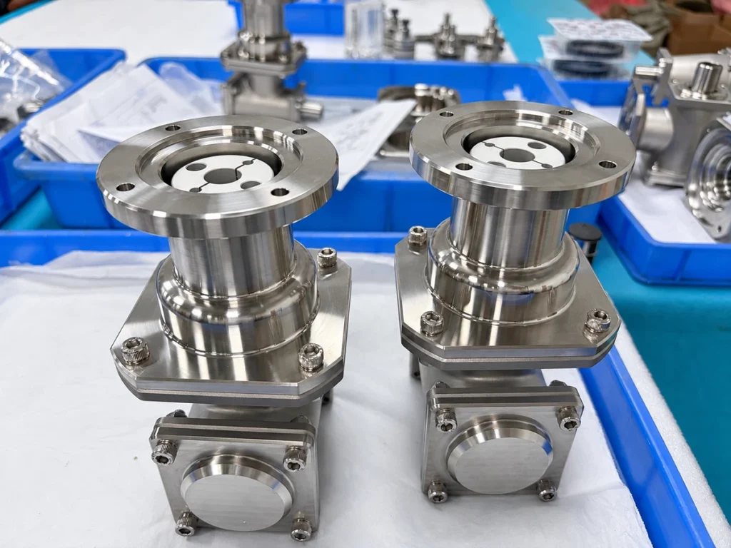 Two metal prototype assemblies with flanged openings and bolted housings on a workshop bench.