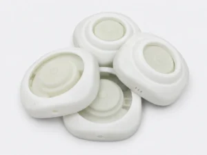 Four white 3D printed prototype housings with recessed centers and side openings
