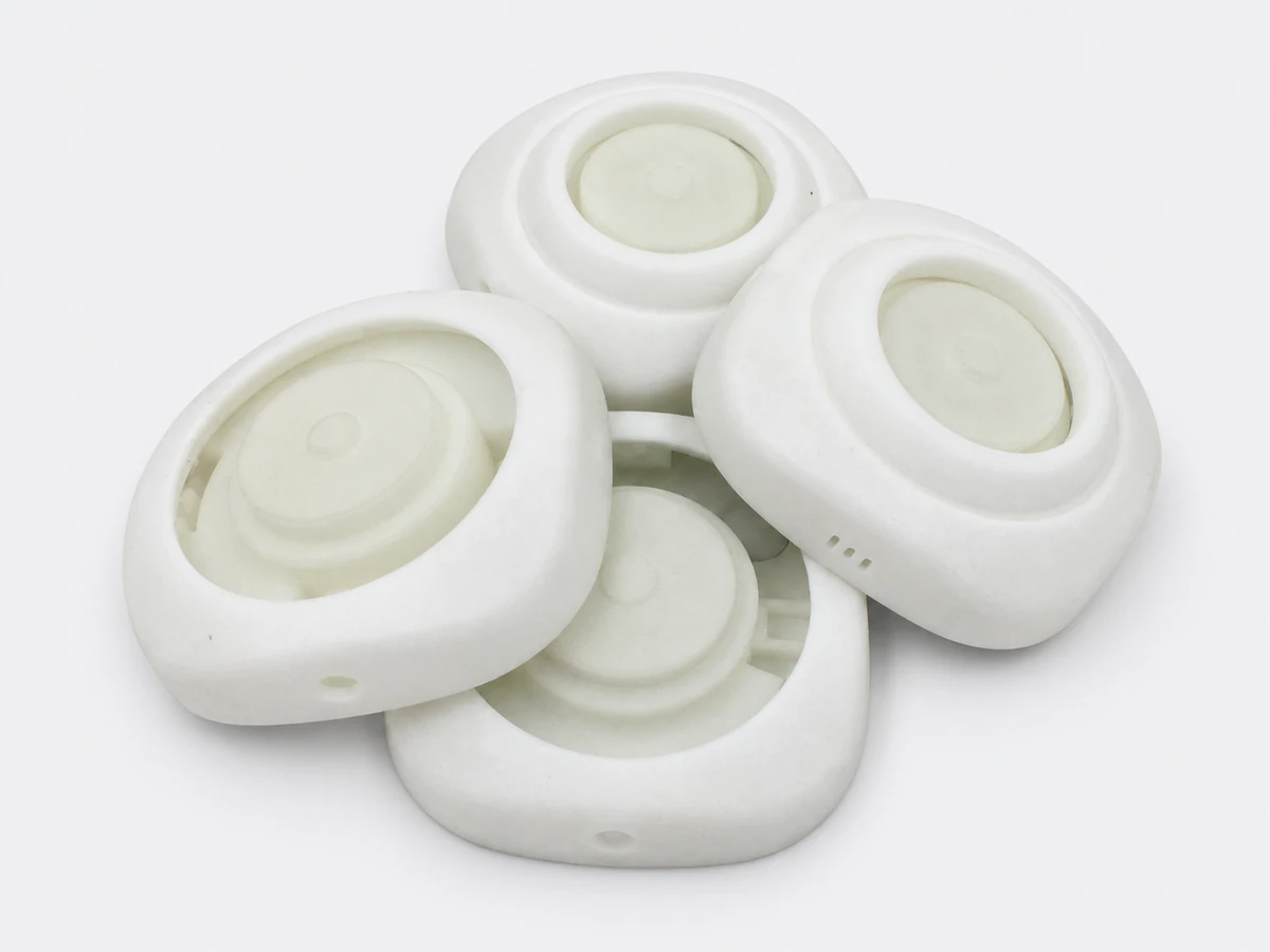 Four white 3D printed prototype housings with recessed centers and side openings