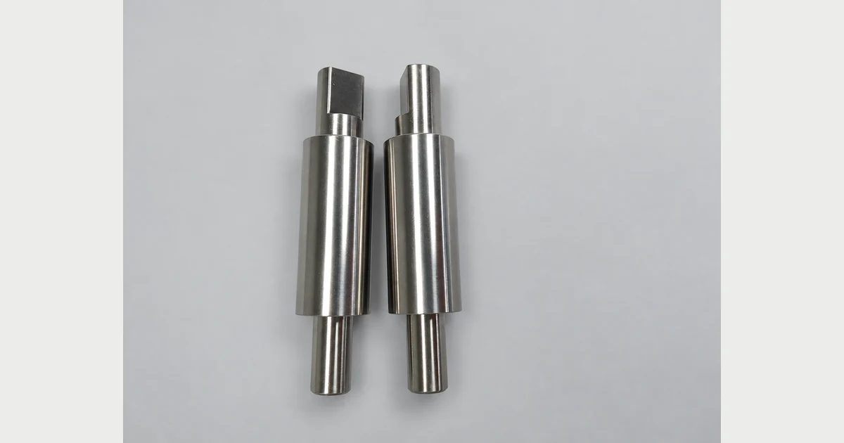 Two machined stepped shafts with cylindrical sections and end flats
