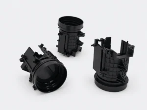 Three black injection molded prototype housings with circular openings and reinforcing ribs