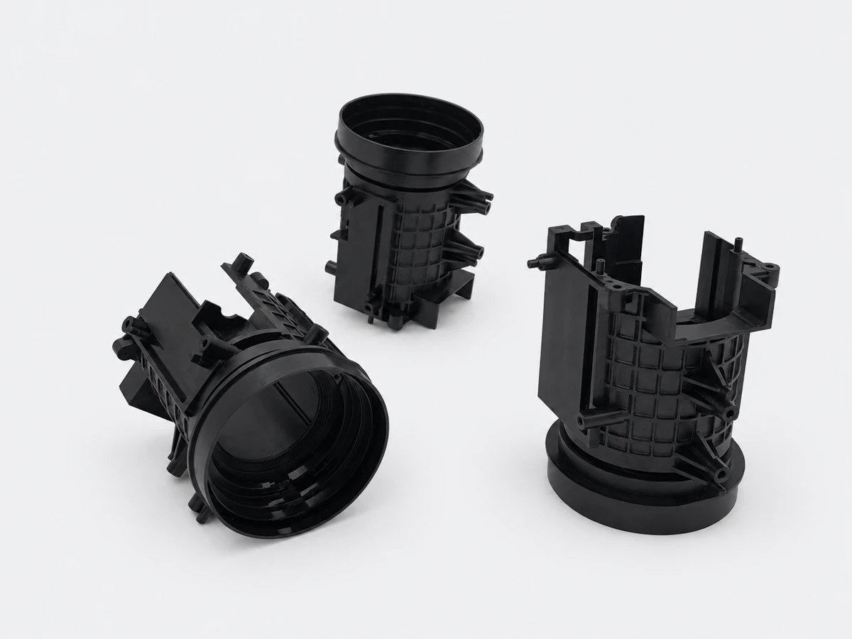 Three black injection molded prototype housings with circular openings and reinforcing ribs
