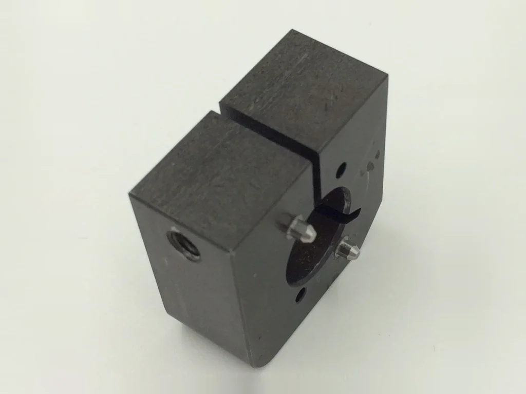 Black oxide finished split machined block with circular openings and contrasting metal details