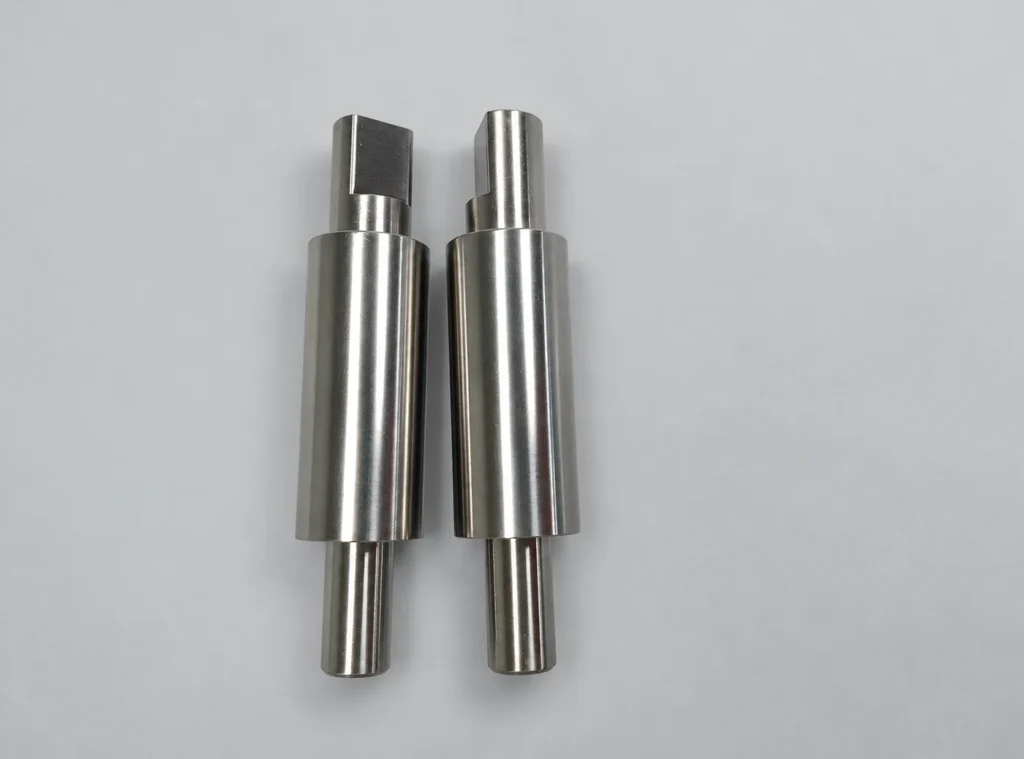 Two CNC machined stepped shafts with cylindrical sections and end flats