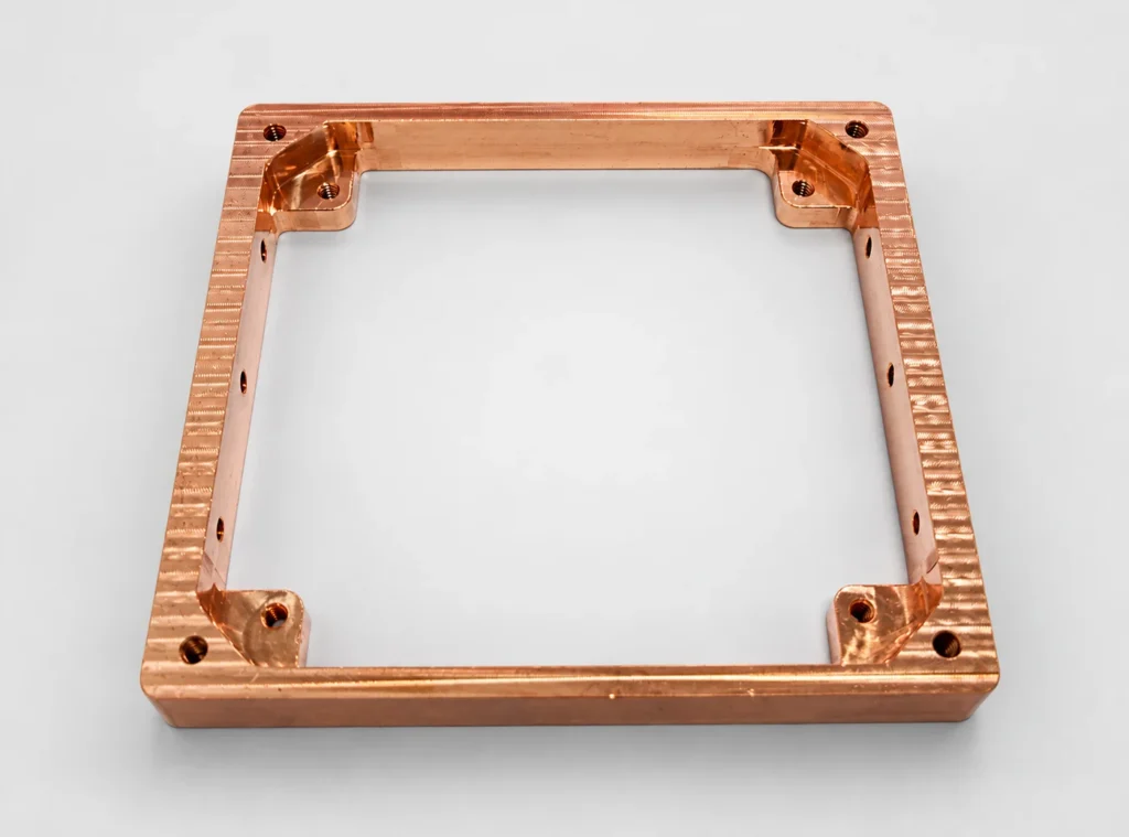 Copper frame CNC milled from solid stock with integral corner pads and mounting holes