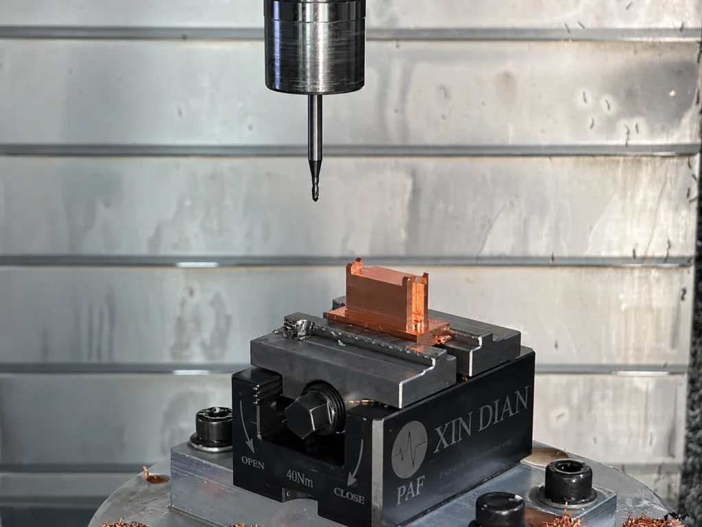 Copper workpiece clamped in a CNC machine vise with the cutting tool positioned above it